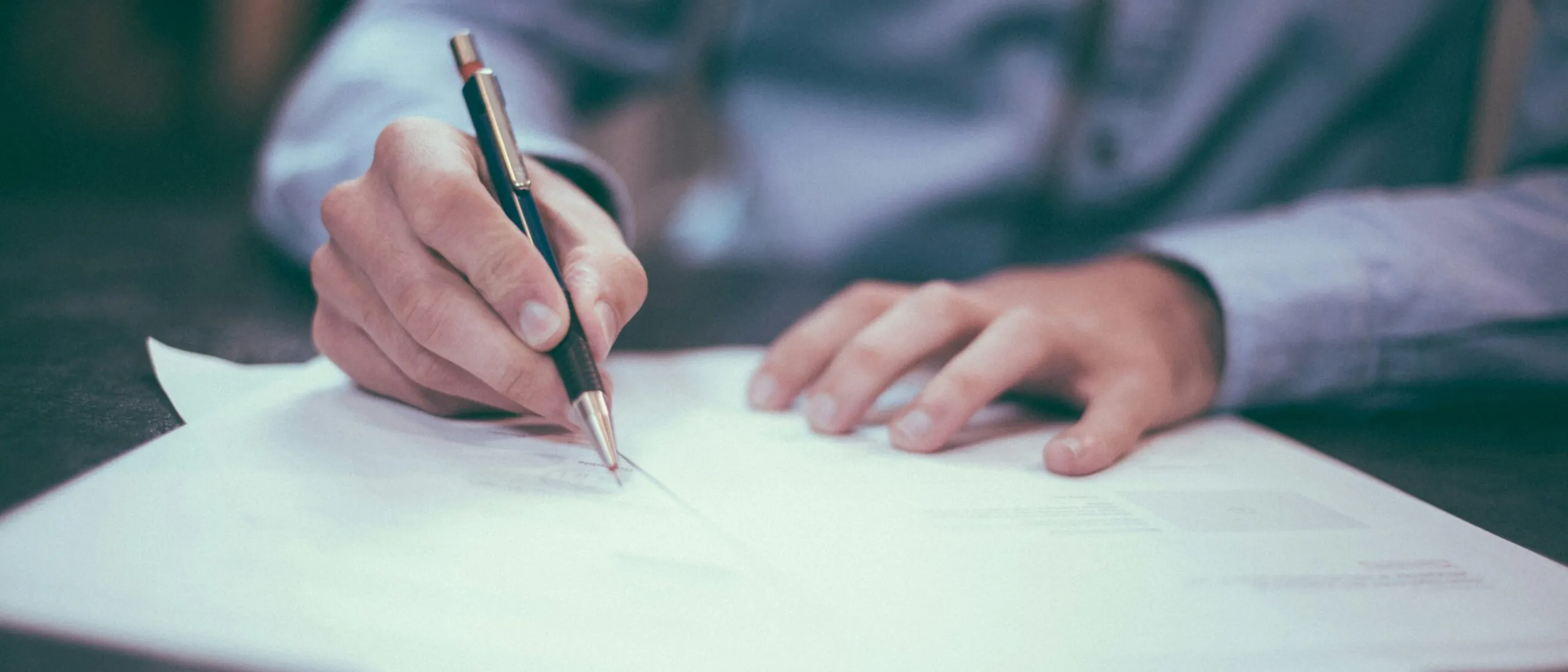 A hand signing an insurance document