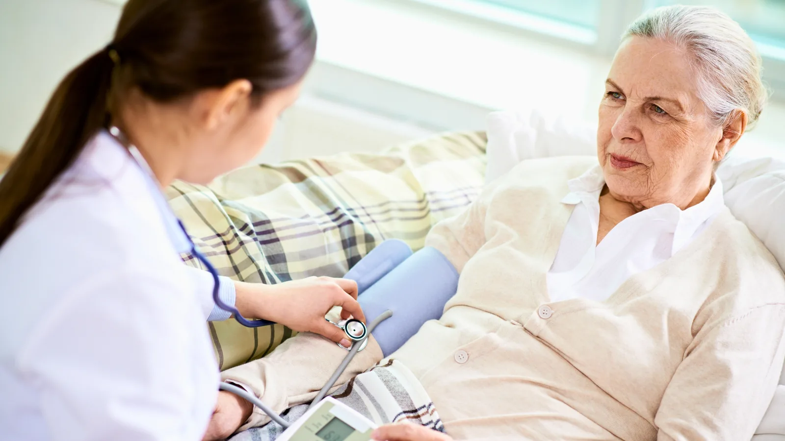 A nurse checking on an elderly patient at home