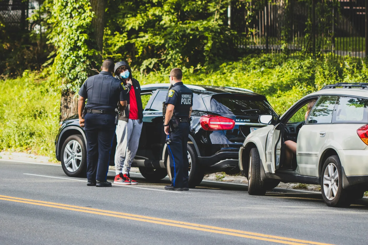 Police officers at the roadside beside two cars after a collision