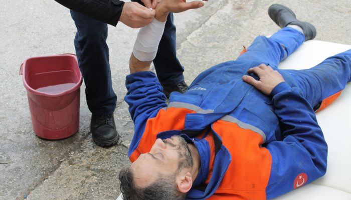 injured worker laying on the ground being helped by another person